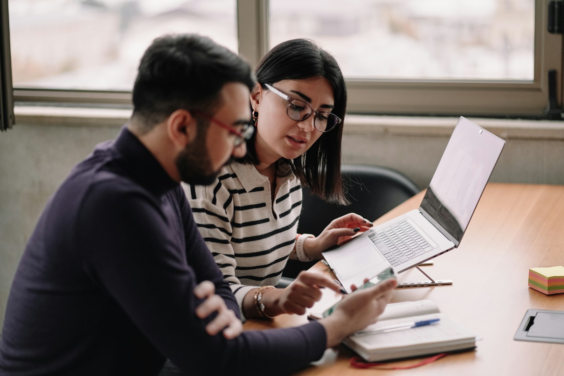 A Latino man and woman working on a government contract at their laptop