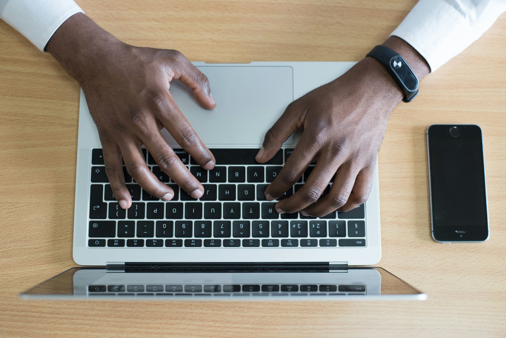 A black man typing on a laptop working on a federal contract to apply for